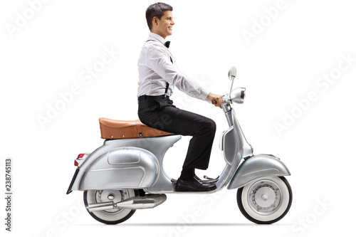 Young man in smart clothes riding a vintage scooter