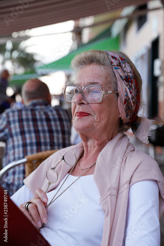 Attractive 78 year old woman during a summer restaurant visit. Authentic, natural, unplugged.