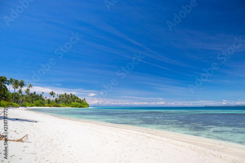 A nice and empty beach in a tropical desert island of Pulau Banyak, Sumatra, Indonesia. Blue sky, white sand and coconut trees, a dream holiday place to relax, snorkel and rest.