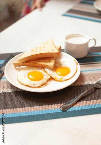 Two fried eggs on a plate with toast for Breakfast