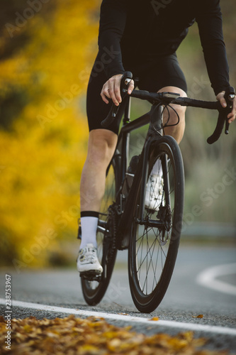 Fototapeta Naklejka Na Ścianę i Meble -  Professional road bicycle racer in action. Men cycling mountain road bike at sunset.