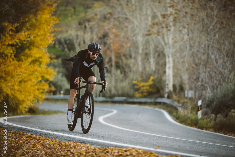 Professional road bicycle racer in action. Men cycling mountain road bike at sunset.