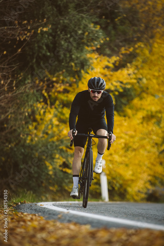 Professional road bicycle racer in action. Men cycling mountain road bike at sunset.