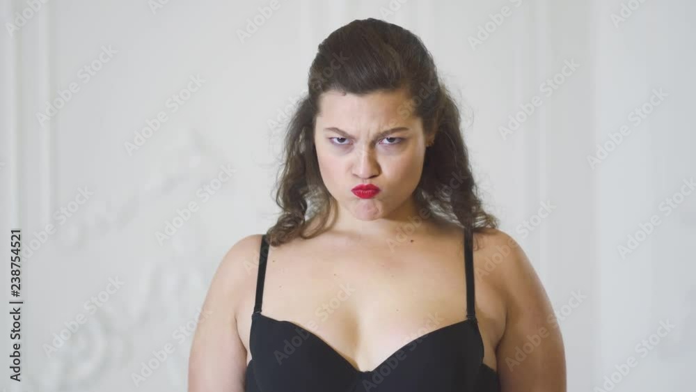 Cute girl in black bra posing on a white background in the studio. Redhead woman in lingerie posing in bright studio. Charming woman smiles and straightens hair. The girl shows emotions. Joy and Cute girl in black bra posing on a white background in the studio. Redhead woman in lingerie posing in bright studio. Charming woman smiles and straightens hair. The girl shows emotions. Joy and