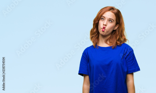 Young beautiful woman over isolated background making fish face with lips, crazy and comical gesture. Funny expression.