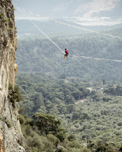 Highliner on a rope. Highline on a background of mountains. Extreme sport on the nature. Balancing on the sling. Equilibrium at altitude.