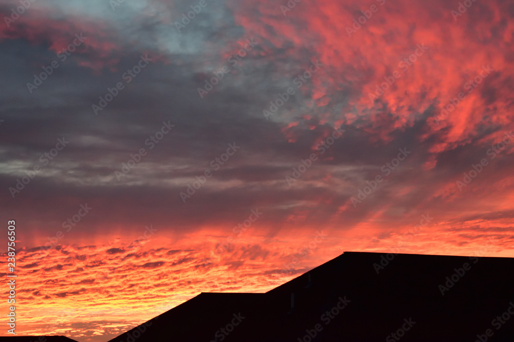 Beautiful sunrise with vivid cloud colors over rooftops  