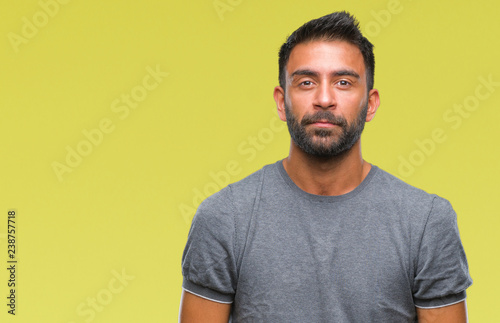 Adult hispanic man over isolated background with serious expression on face. Simple and natural looking at the camera.