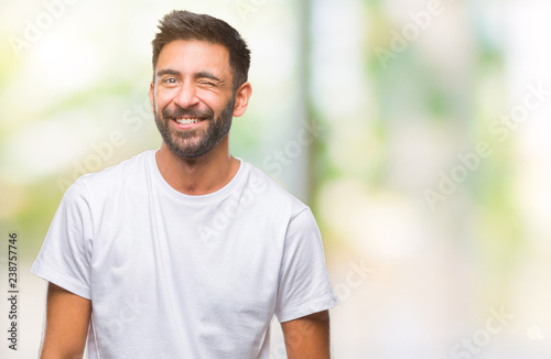 Adult hispanic man over isolated background winking looking at the camera with sexy expression, cheerful and happy face.