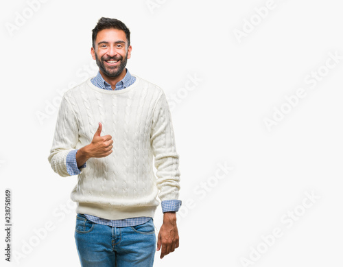 Adult hispanic man wearing winter sweater over isolated background doing happy thumbs up gesture with hand. Approving expression looking at the camera with showing success.