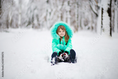 Funny little girl having fun in beautiful park during snowfall