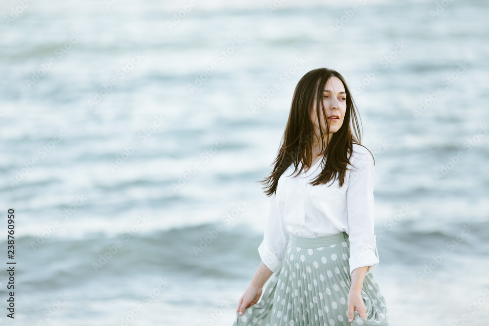 Marine female portrait. Attractive woman in green skirt walks along the shore before the sea Marine female portrait. Attractive woman in green skirt walks along the shore before the sea