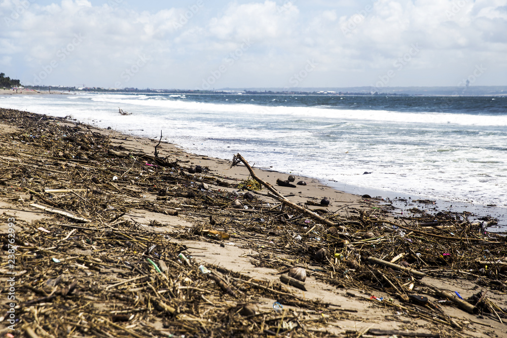 Spilled garbage on the beach closed to ocean. Environmental pollution.