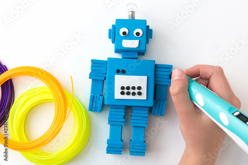 A child, teen boy makes a plastic robot, draws its parts with a 3D pen. STEM and STEAM education. Development, modeling, design and programming of the robot. Modern technologies. DIY.