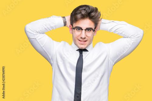 Young business man wearing glasses over isolated background Relaxing and stretching with arms and hands behind head and neck, smiling happy