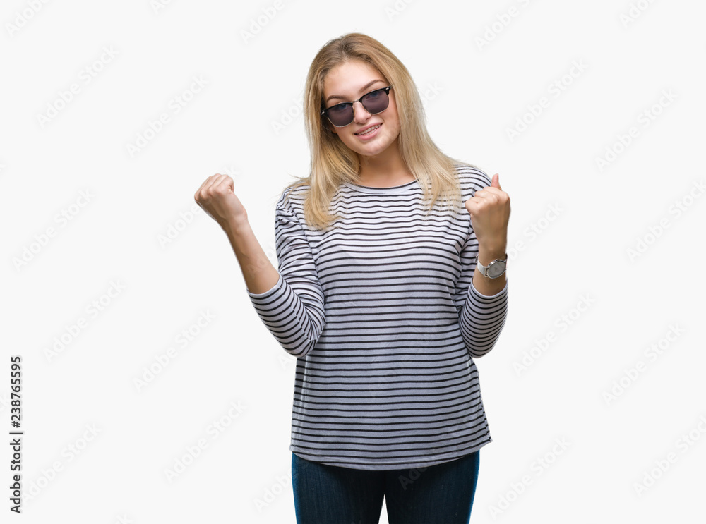 Young caucasian woman wearing sunglasses over isolated background celebrating surprised and amazed for success with arms raised and open eyes. Winner concept. Young caucasian woman wearing sunglasses over isolated background celebrating surprised and amazed for success with arms raised and open eyes. Winner concept.