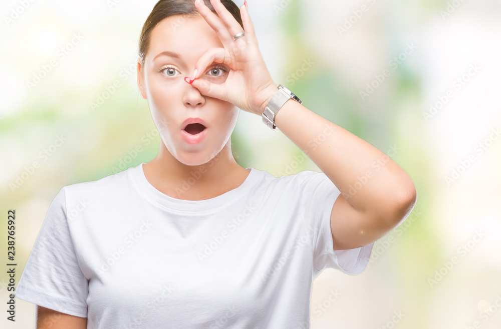 Young beautiful caucasian woman over isolated background doing ok gesture shocked with surprised face, eye looking through fingers. Unbelieving expression. Young beautiful caucasian woman over isolated background doing ok gesture shocked with surprised face, eye looking through fingers. Unbelieving expression.