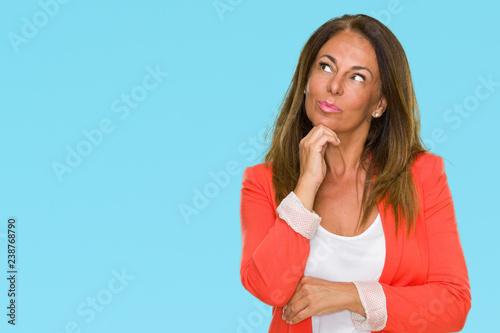 Beautiful middle age business adult woman over isolated background with hand on chin thinking about question  pensive expression. Smiling with thoughtful face. Doubt concept.