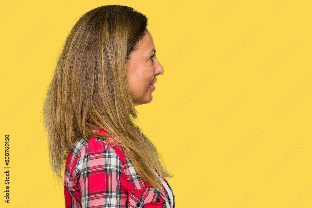 Middle age adult woman wearing casual shirt over isolated background looking to side, relax profile pose with natural face with confident smile. Middle age adult woman wearing casual shirt over isolated background looking to side, relax profile pose with natural face with confident smile.