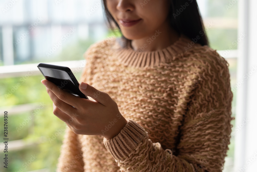 Close-up of content lady in sweater reading online article on smartphone. Modern woman searching for information. Online communication concept Close-up of content lady in sweater reading online article on smartphone. Modern woman searching for information. Online communication concept