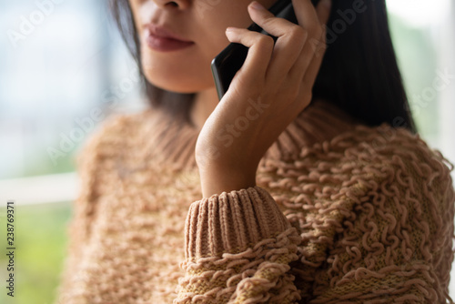 Close-up of lady using mobile phone for important communication. Serious busy woman in sweater talking on cellphone. Business concept