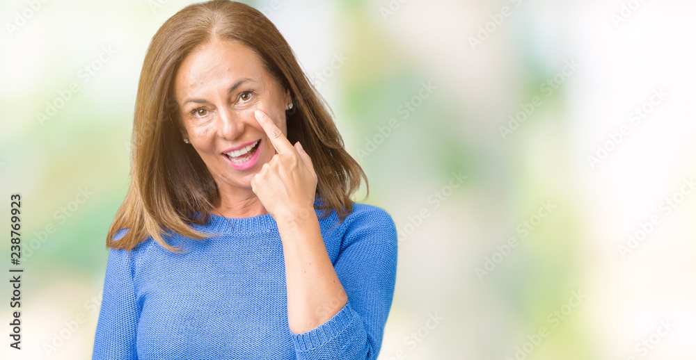 Middle age beautiful woman wearing winter sweater over isolated background Pointing to the eye watching you gesture, suspicious expression