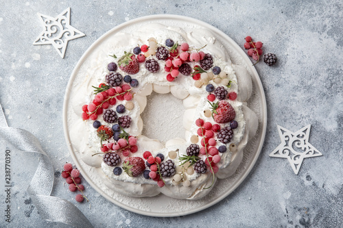 Meringue pavlova wreath cakes with whipped cream and frozen berries photo