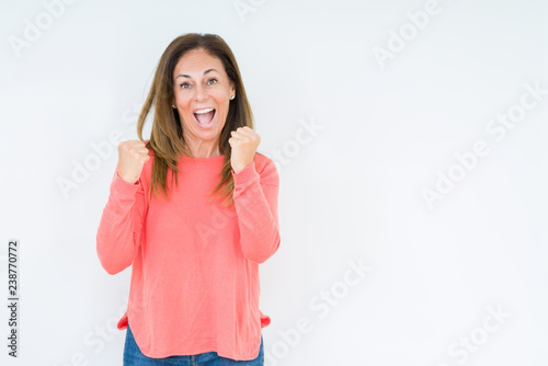 Beautiful middle age woman over isolated background very happy and excited doing winner gesture with arms raised  smiling and screaming for success. Celebration concept.