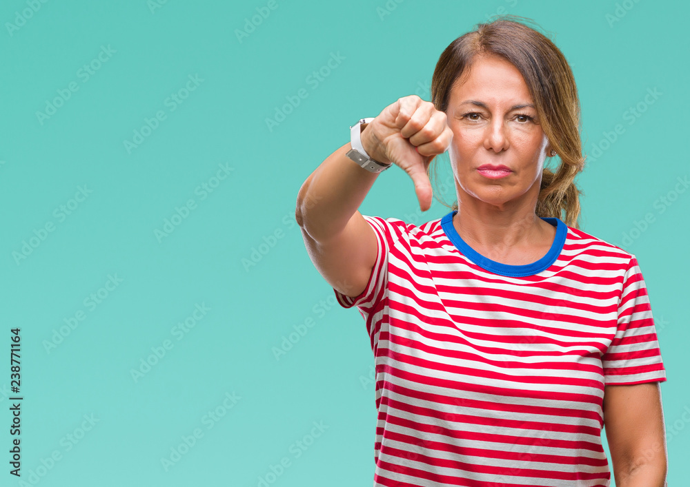 Middle age senior hispanic woman over isolated background looking unhappy and angry showing rejection and negative with thumbs down gesture. Bad expression. Middle age senior hispanic woman over isolated background looking unhappy and angry showing rejection and negative with thumbs down gesture. Bad expression.