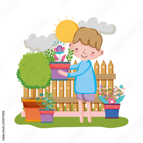 boy lifting houseplant with fence in the garden