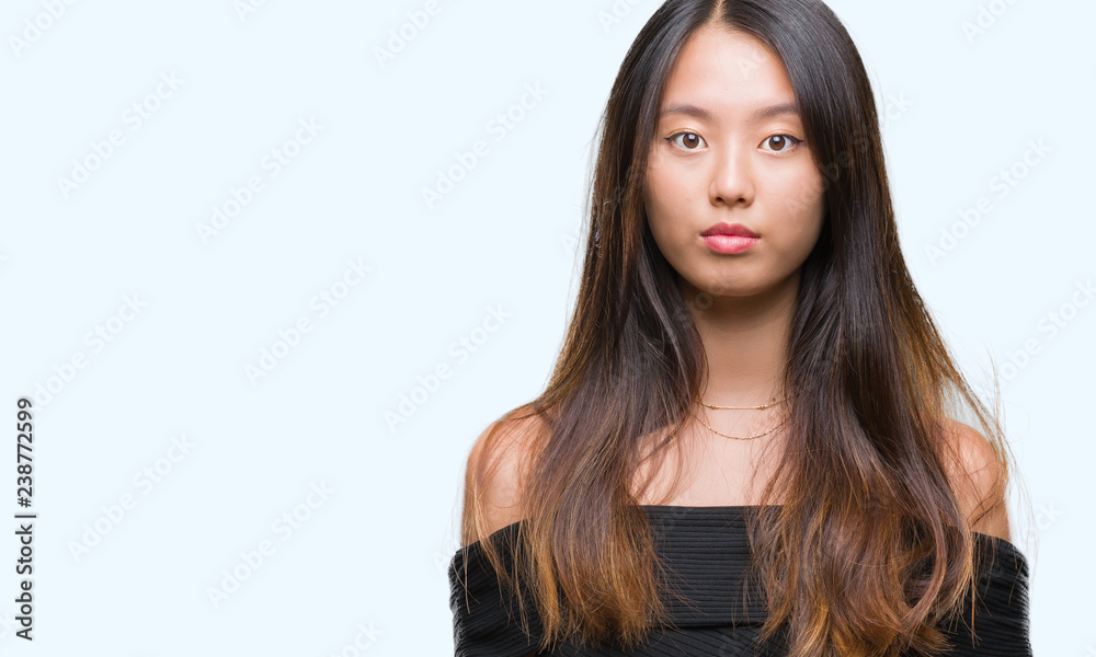 Young asian woman over isolated background with serious expression on face. Simple and natural looking at the camera. Young asian woman over isolated background with serious expression on face. Simple and natural looking at the camera.