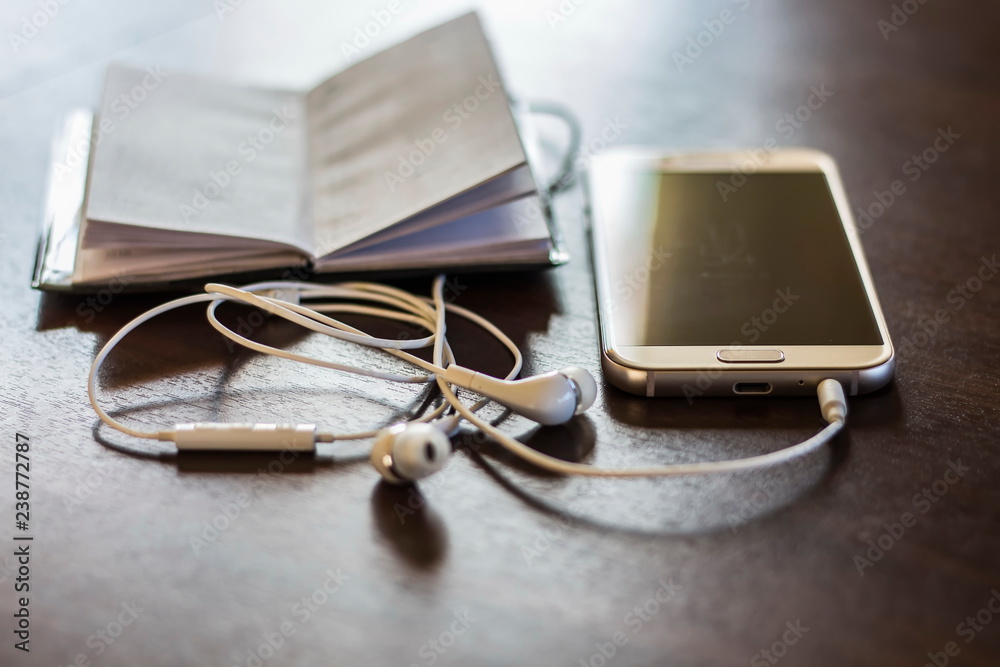 Phone next to a pair of earphones. Phone next to a pair of earphones.
