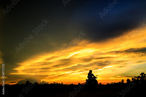 silhouette of  by motorcycle on background of sunset sky