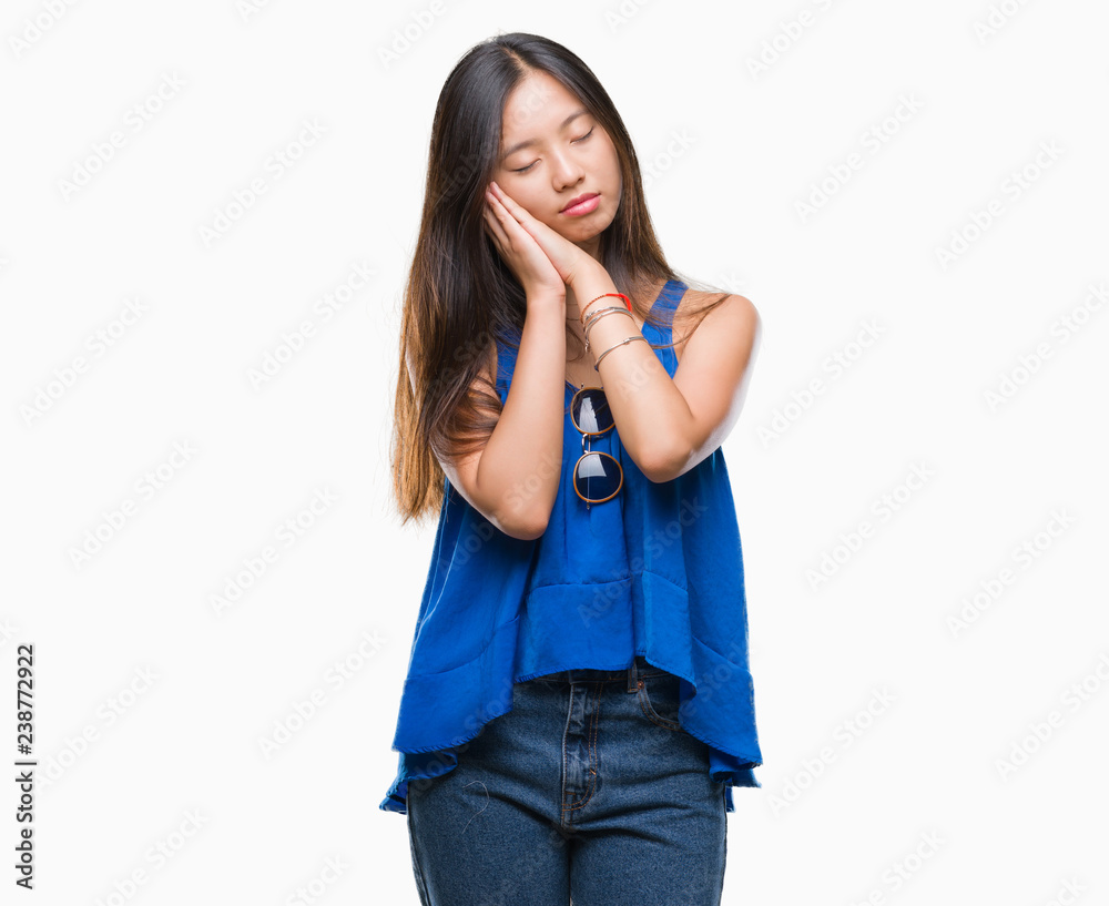 Young asian woman over isolated background sleeping tired dreaming and posing with hands together while smiling with closed eyes. Young asian woman over isolated background sleeping tired dreaming and posing with hands together while smiling with closed eyes.