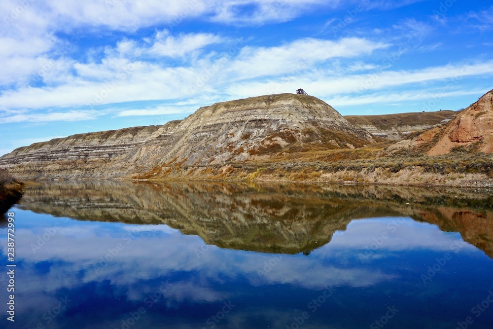 Badland rock formations reflected in river