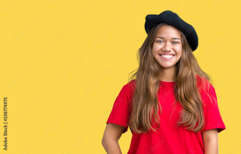 Young beautiful brunette fashion woman wearing red t-shirt and black beret over isolated background with a happy and cool smile on face. Lucky person. Young beautiful brunette fashion woman wearing red t-shirt and black beret over isolated background with a happy and cool smile on face. Lucky person.