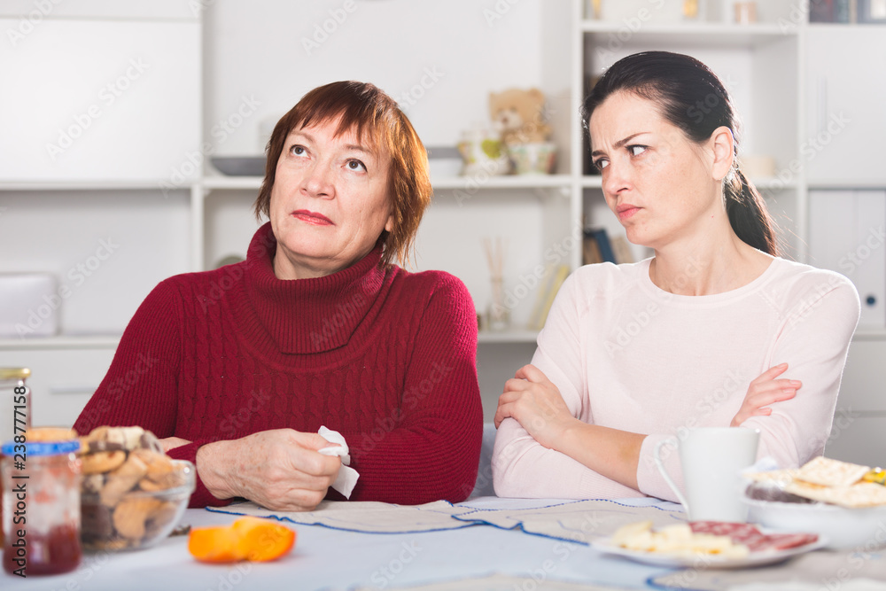 Unhappy adult female quarrel with daughter at table