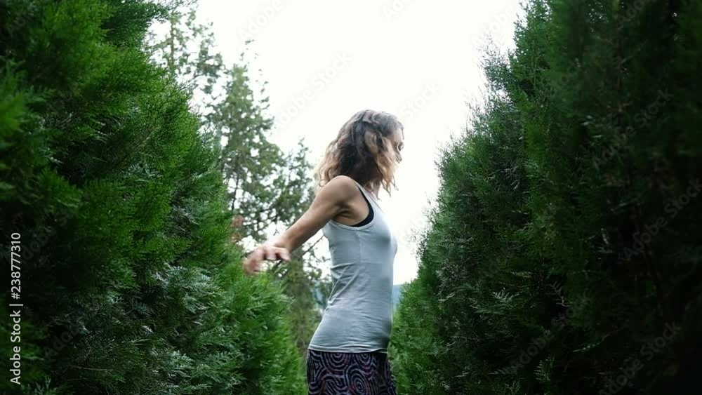 Happy woman spinning around herself among spruce and fluffy bushes, slow motion Happy woman spinning around herself among spruce and fluffy bushes, slow motion