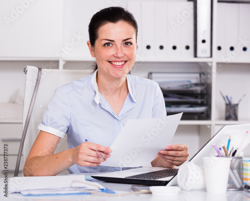 Smiling office worker sitting with documents