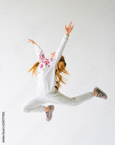 Beautiful gymnast girl in grey sportswear, performing art gymnastics element, jumping, doing split leap in the air