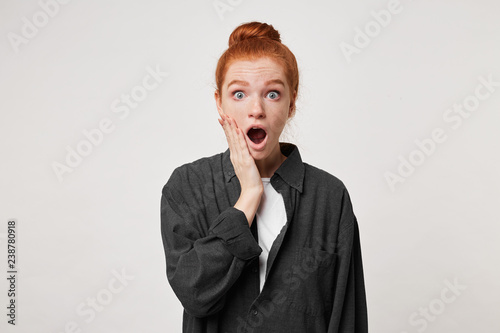 Obraz na plátně Red-haired girl stands in a daze, shocked by what she saw, with wide eyes lookin
