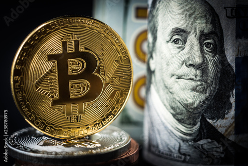 Gold bitcoin coin standing in front of dollar bills. New virtual money concept