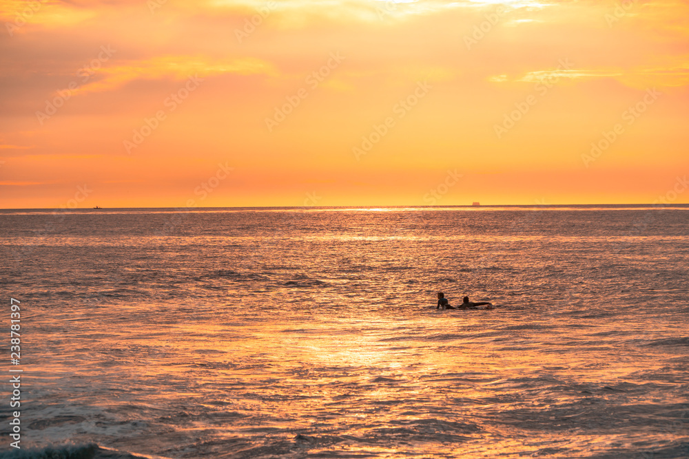 Surfers are waiting for waves on beautiful sunset