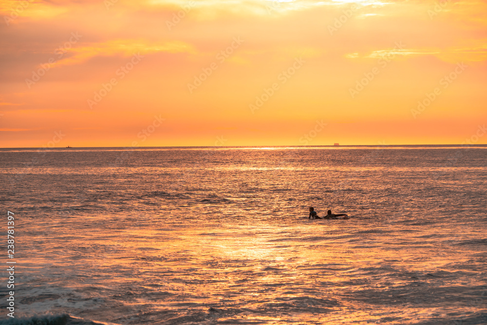Surfers are waiting for waves on beautiful sunset Surfers are waiting for waves on beautiful sunset