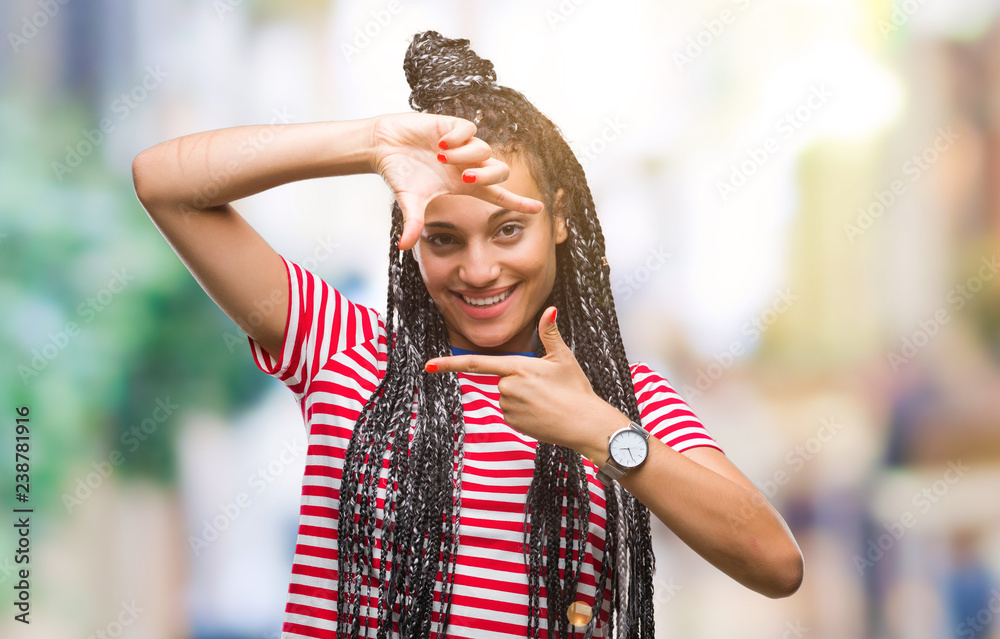 Young braided hair african american girl over isolated background smiling making frame with hands and fingers with happy face. Creativity and photography concept.