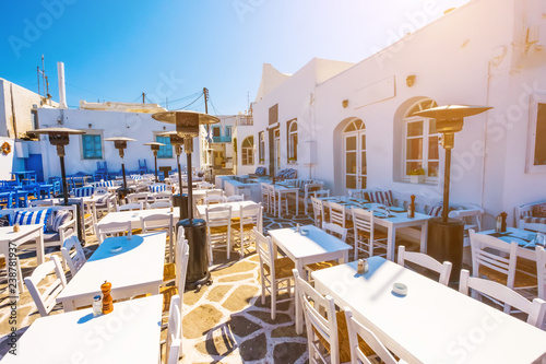 Tables and chairs outdoors in traditional Greek cafe. Typical Greek taverna in Naoussa port, Paros island, Greece