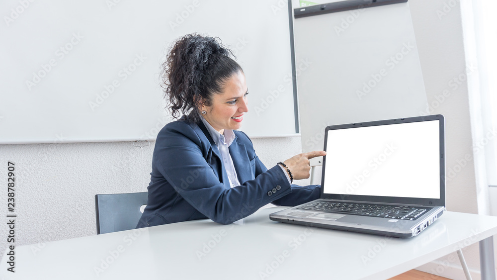 Portrait of a normal business woman pointing at the white laptop screen in a office desk. With copy space. Dressing professionally looking at the computer Portrait of a normal business woman pointing at the white laptop screen in a office desk. With copy space. Dressing professionally looking at the computer