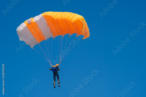 Skydiver is flying with parachute in blue sky