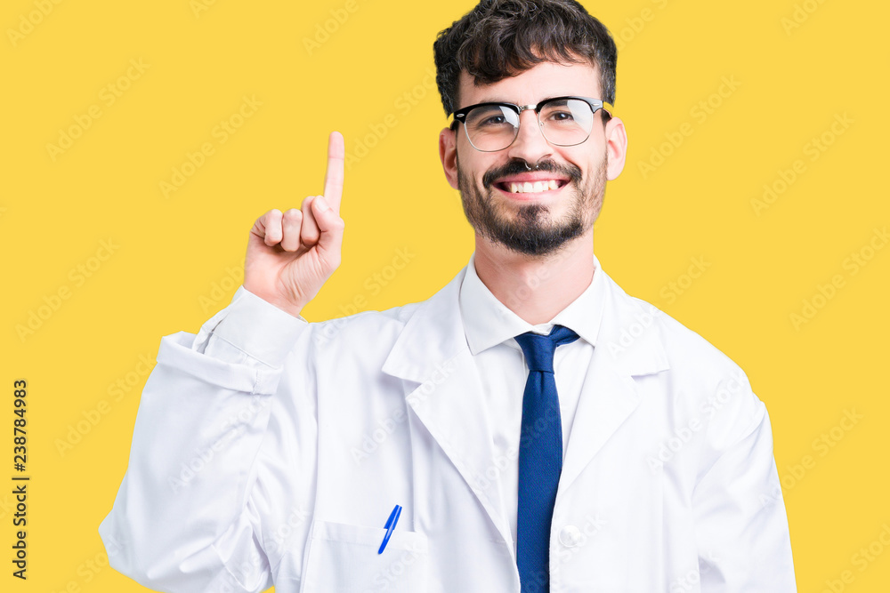 Young professional scientist man wearing white coat over isolated background showing and pointing up with finger number one while smiling confident and happy.