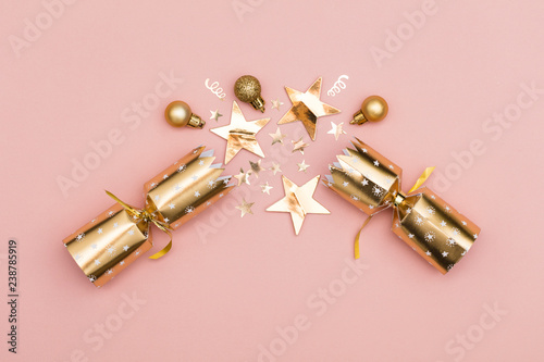 Christmas crackers. luxury gold festive cracker on a pastel pink background